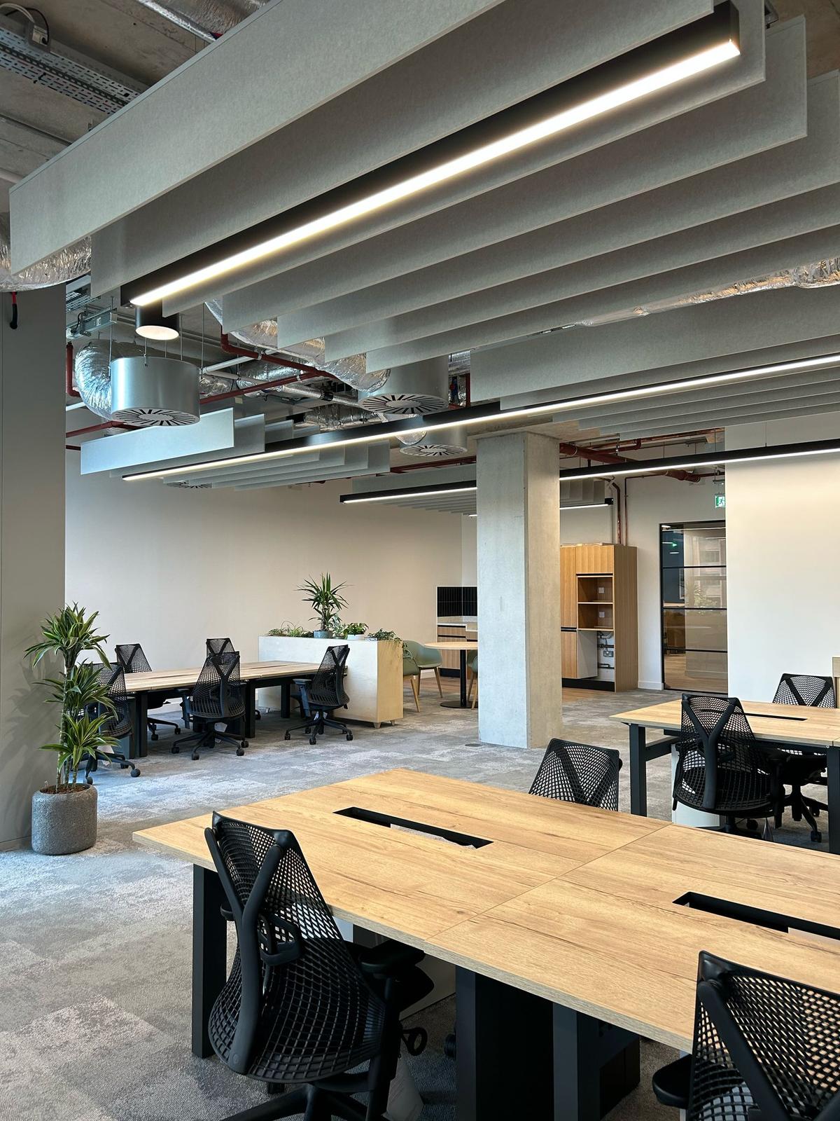 Open-plan office with wooden desks and concrete pillars